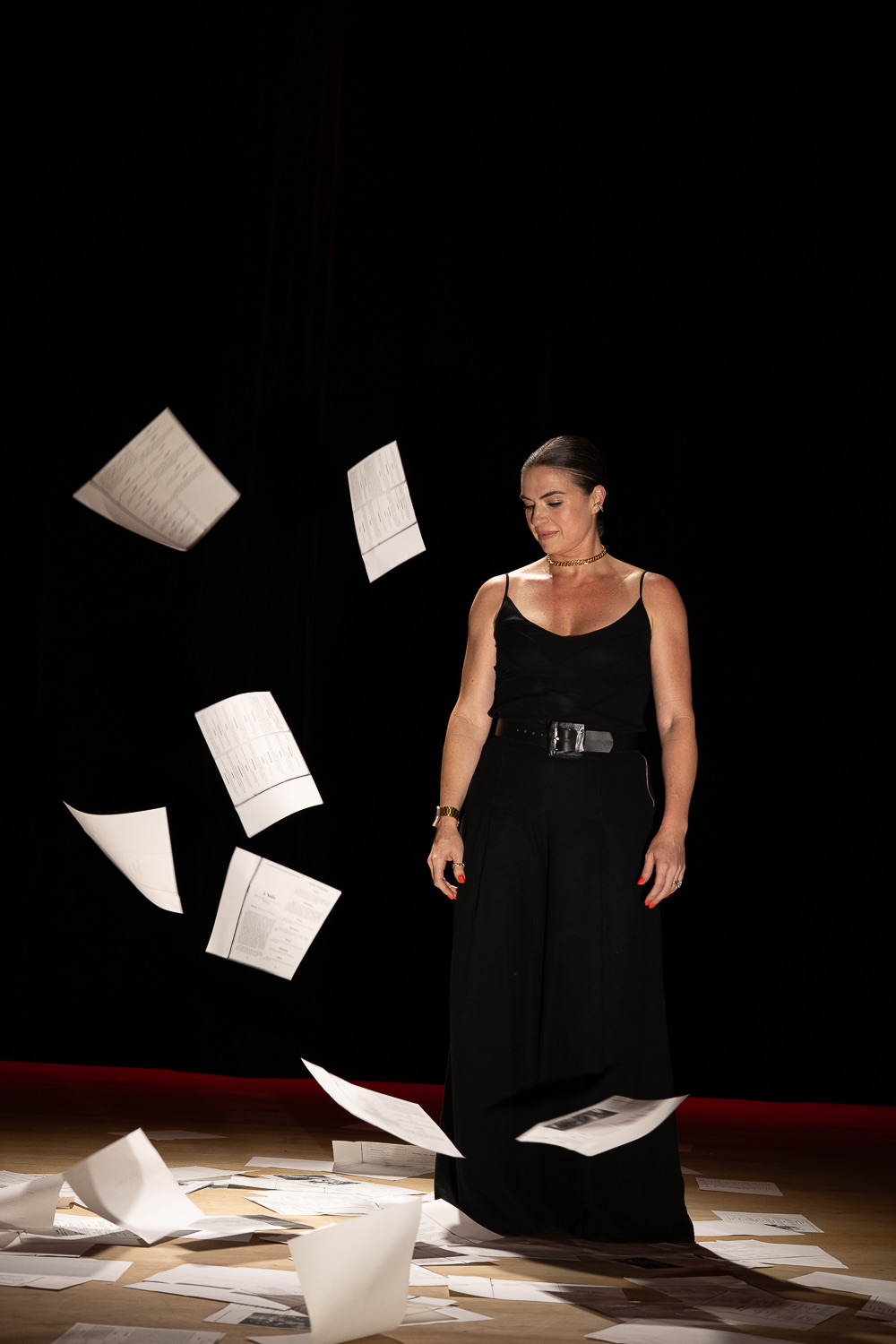 Gaby Haviaras em palco, papéis dispersos ao redor